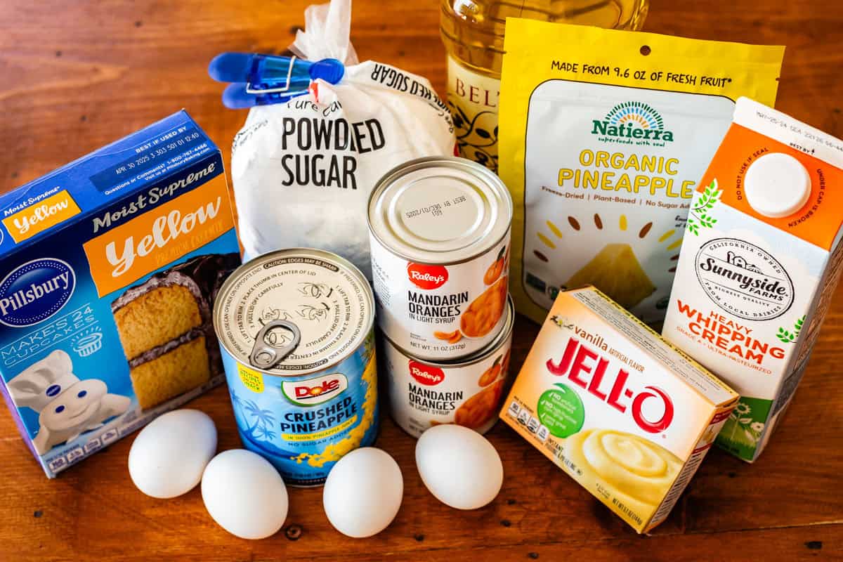 wooden table with yellow cake mix, whipping cream, and other ingredients for pig pickin cake.
