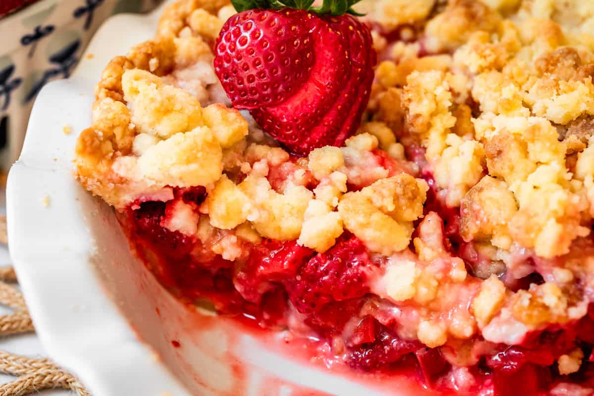 baked strawberry rhubarb pie with crumble topping in pie pan with slice removed.
