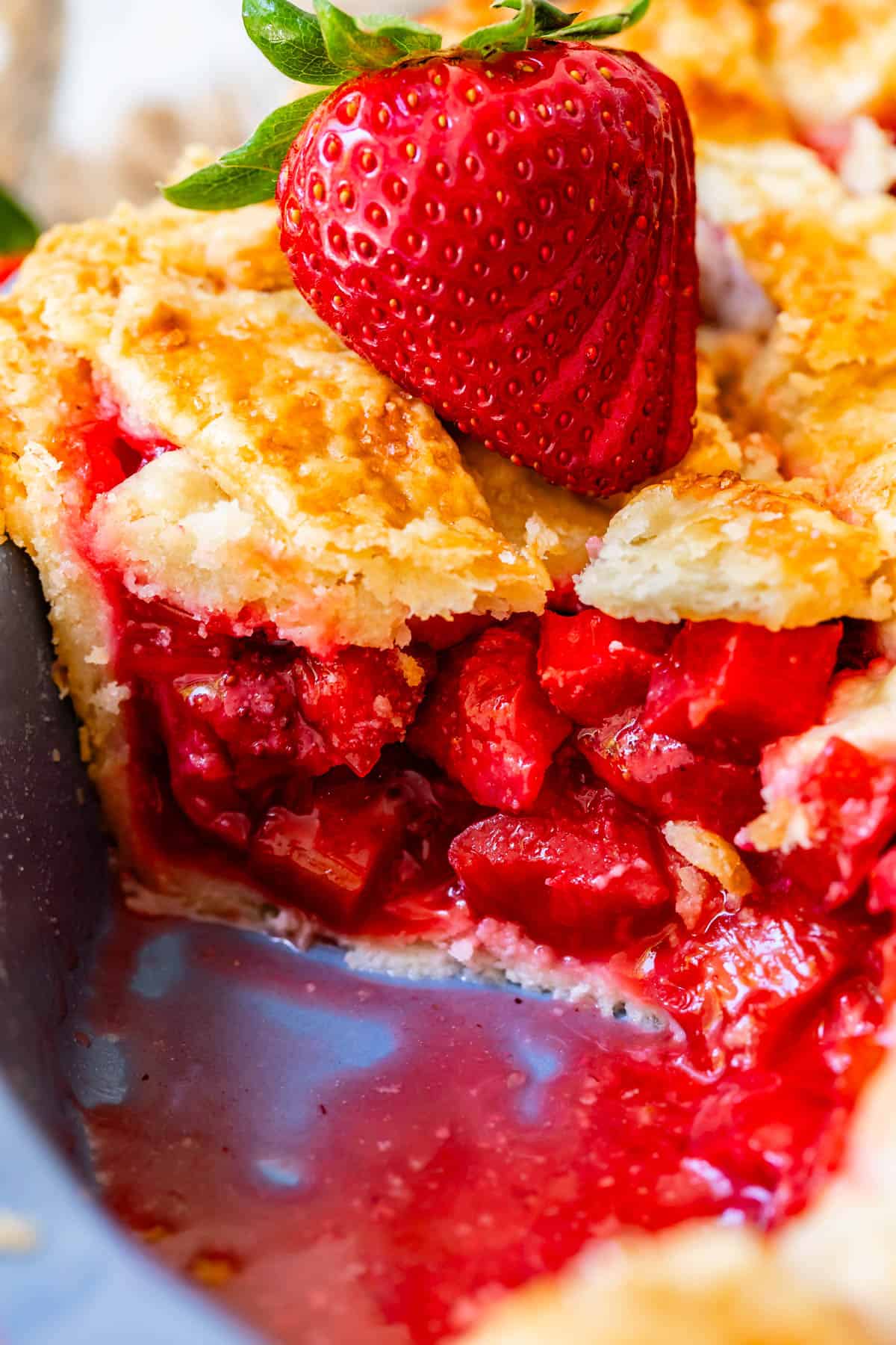 looking at the side of a piece of pie with all the strawberry and rhubarb filling showing.