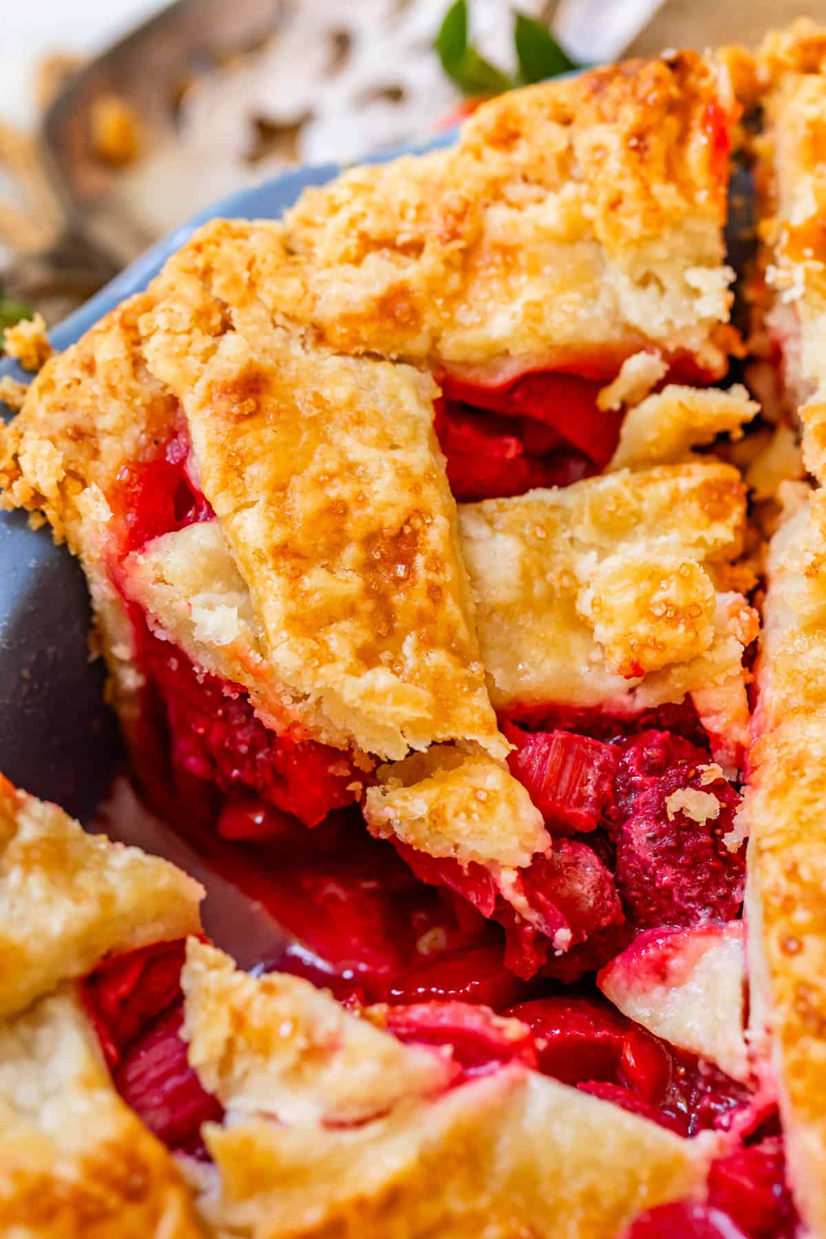 a piece of strawberry rhubarb pie in the pan with flaky lattice crust.