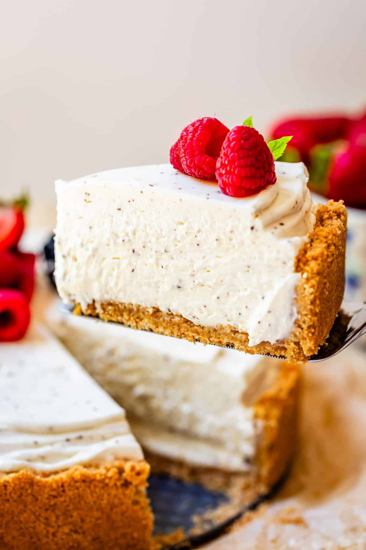 a pie server holding a perfectly sliced no bake cheesecake with remaining cheesecake in background.