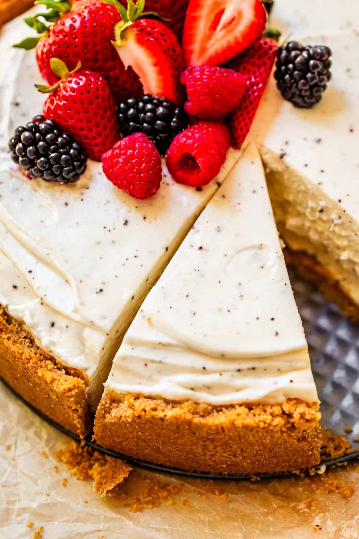 no bake cheesecake with fresh berry garnish, with one slice missing and a second slice cut.