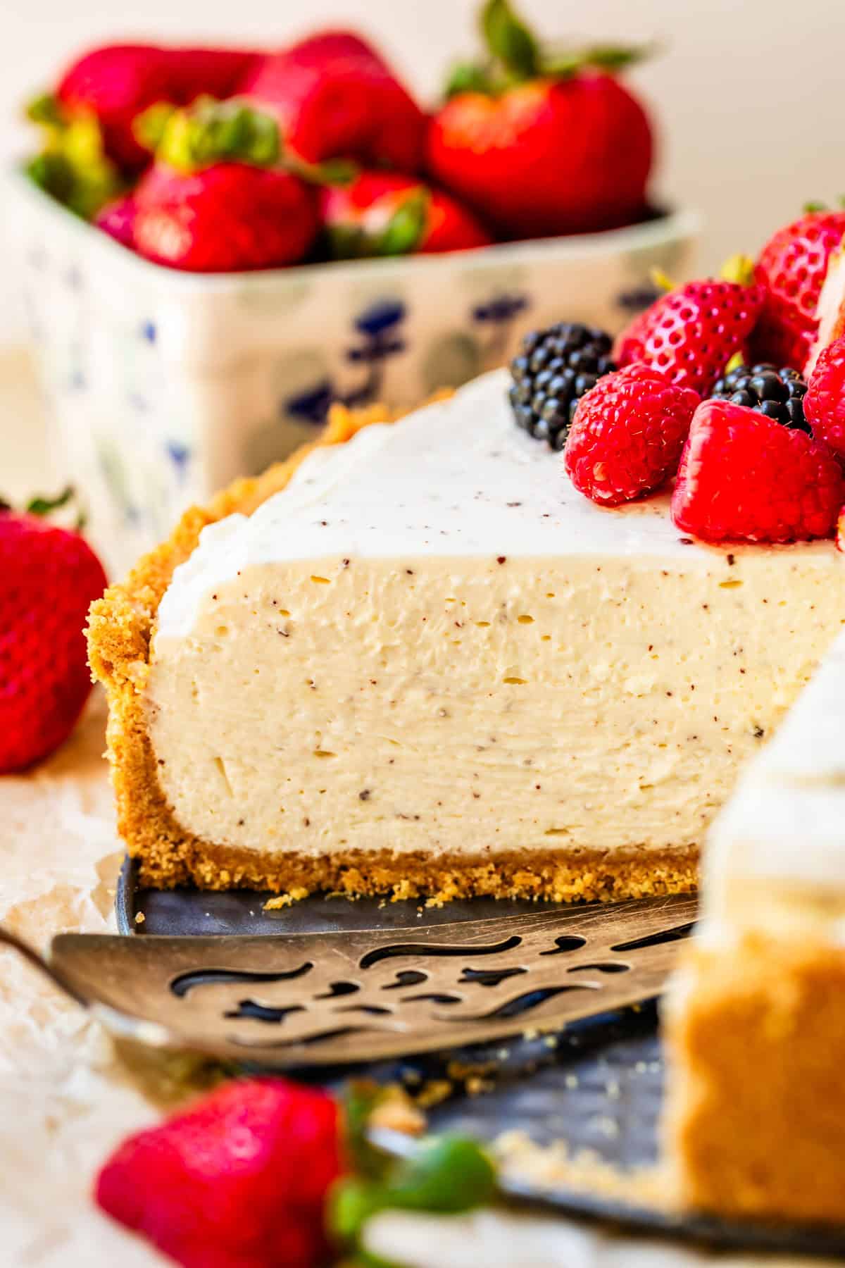 side view of a no bake cheesecake with a piece cut out of it and fresh berry topping.