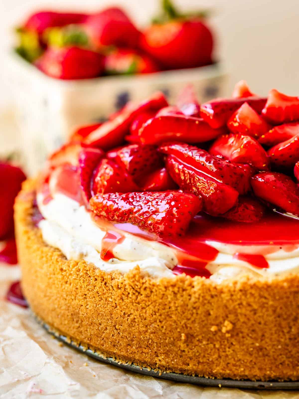 side view of a whole no bake cheesecake smothered with fresh strawberry topping.