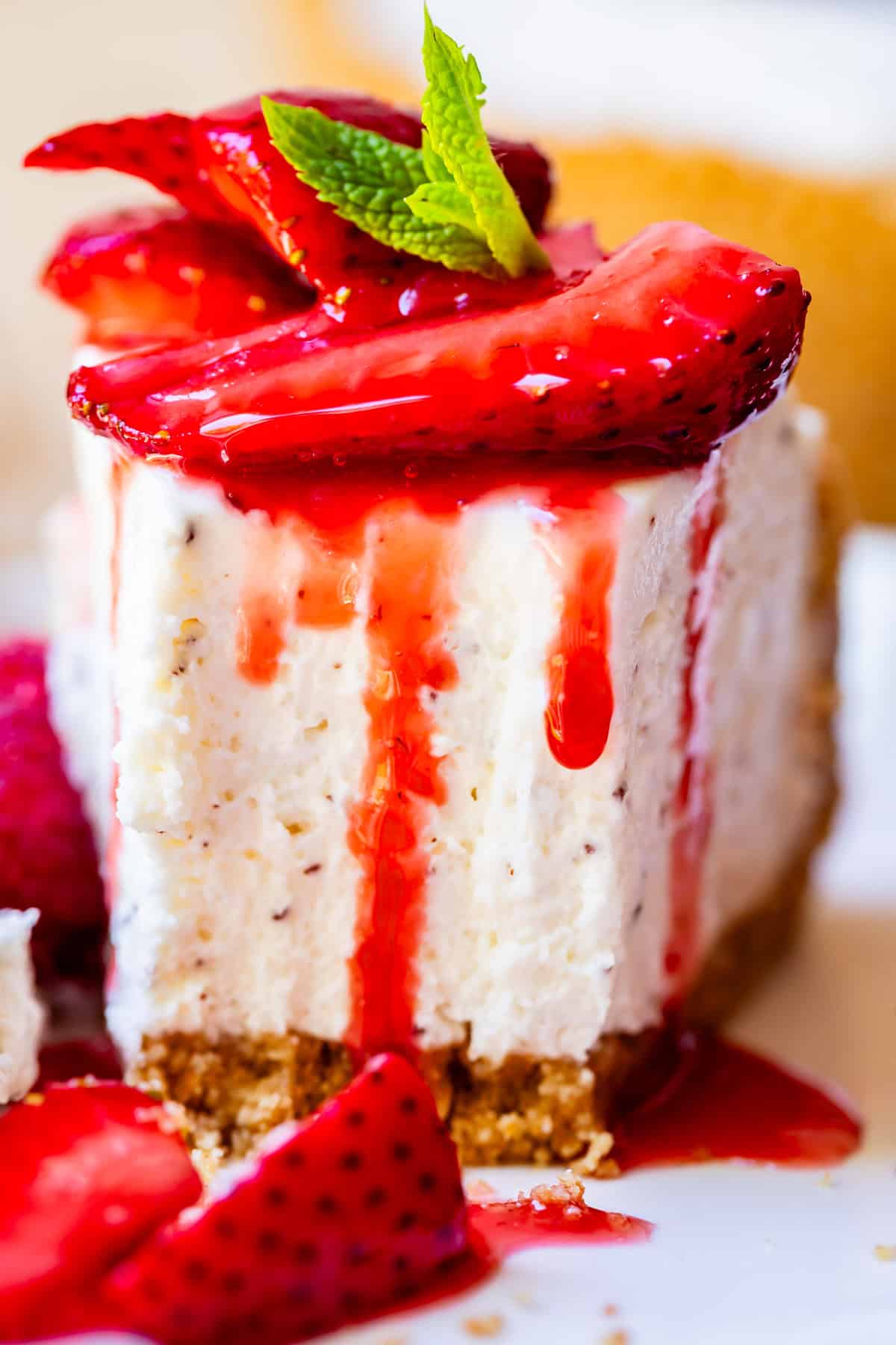 slice of no bake cheesecake on a white plate with bites taken out, topped with strawberries.