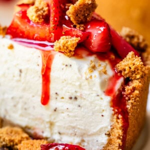 side view of a slice of no bake cheesecake with strawberry topping and graham crumble on top.