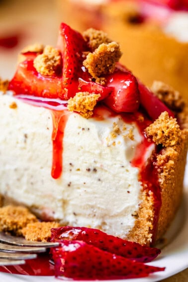 side view of a slice of no bake cheesecake with strawberry topping and graham crumble on top.