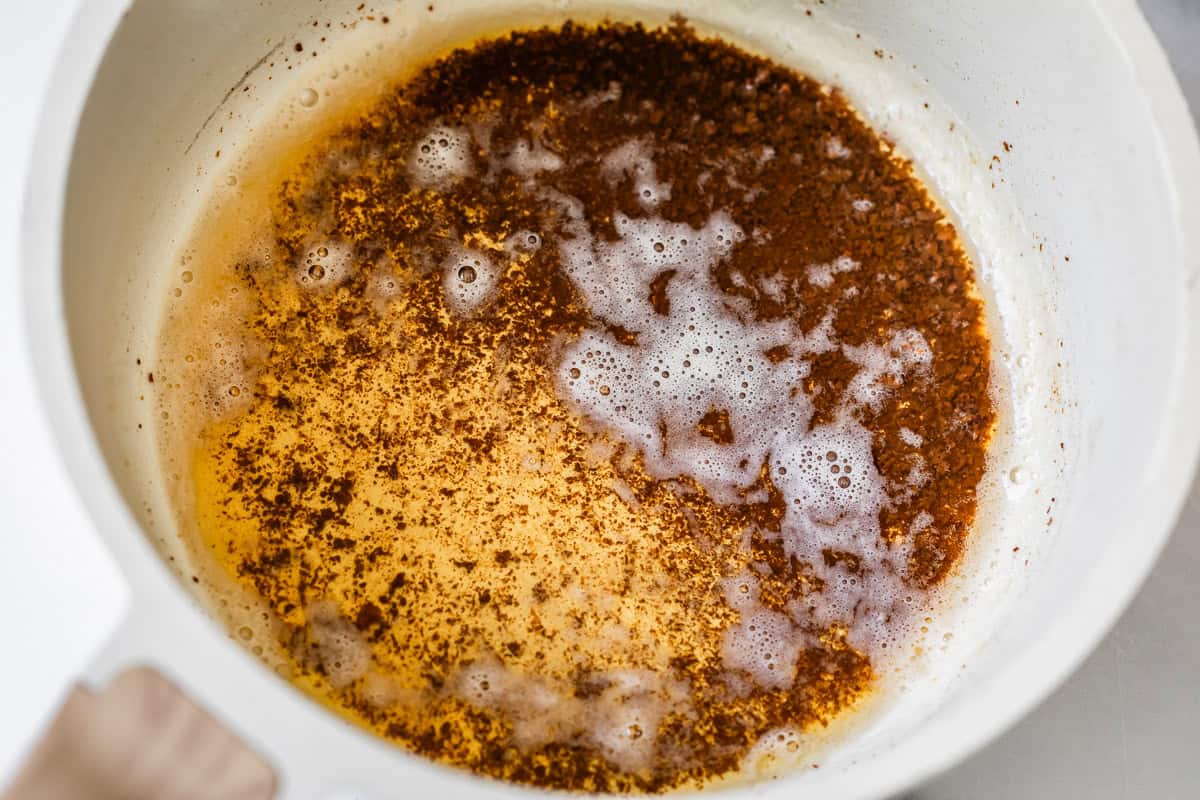 browned butter in a white cookpot showing the clarified butter with browned bits in it.