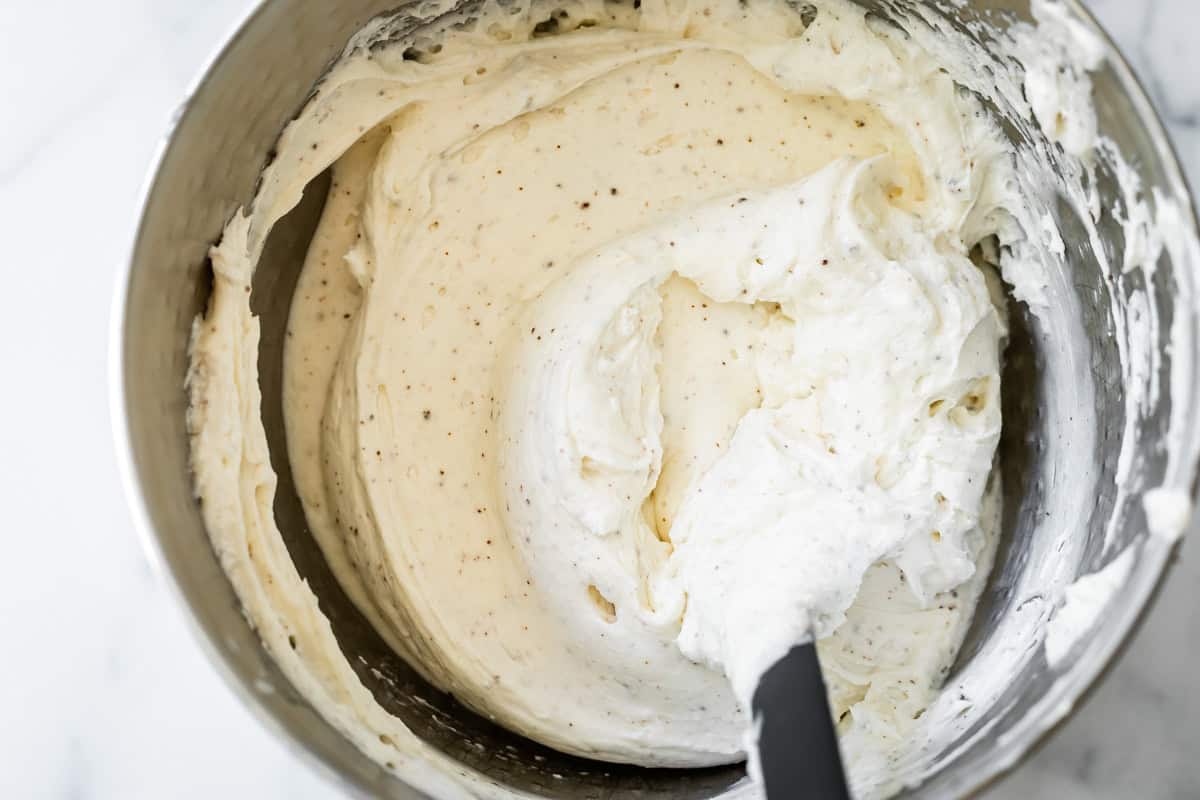 cheesecake filling with flecks of browned butter bits, in a metal mixing bowl. 