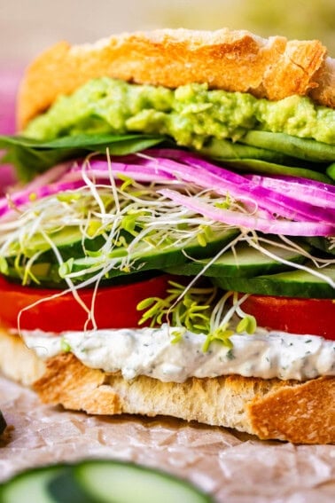 sourdough, spread, tomato, cucumber, sprouts, onion, spinach, guac sandwich.