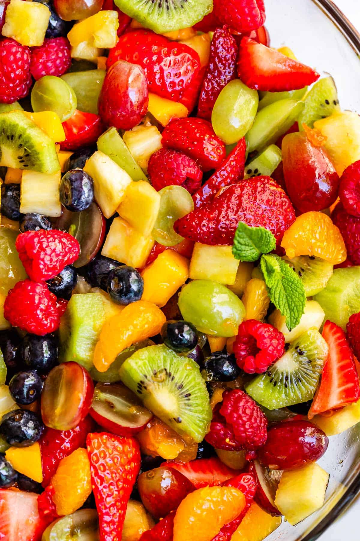 glass bowl filled to the top with mixed together fruit salad covered in glaze.