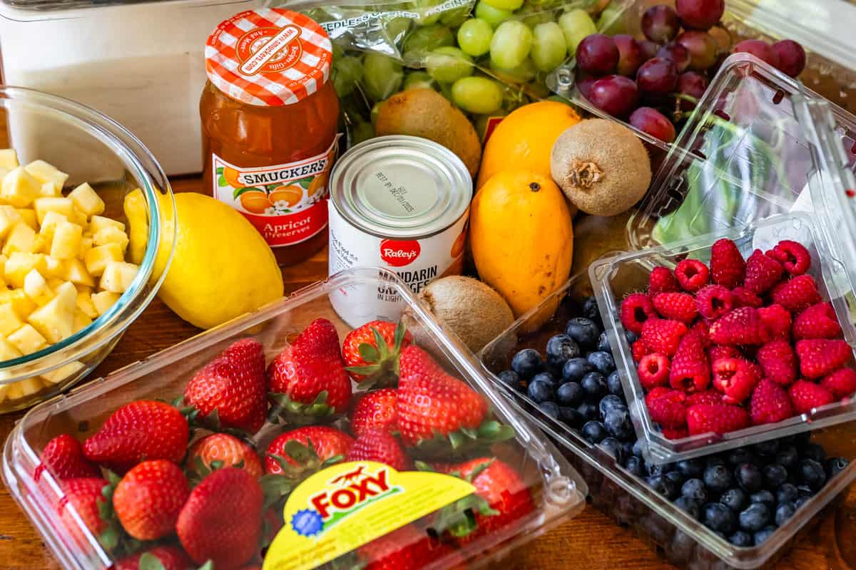 ingredients for fruit salad like berries, mango, apricot preserves, and more.