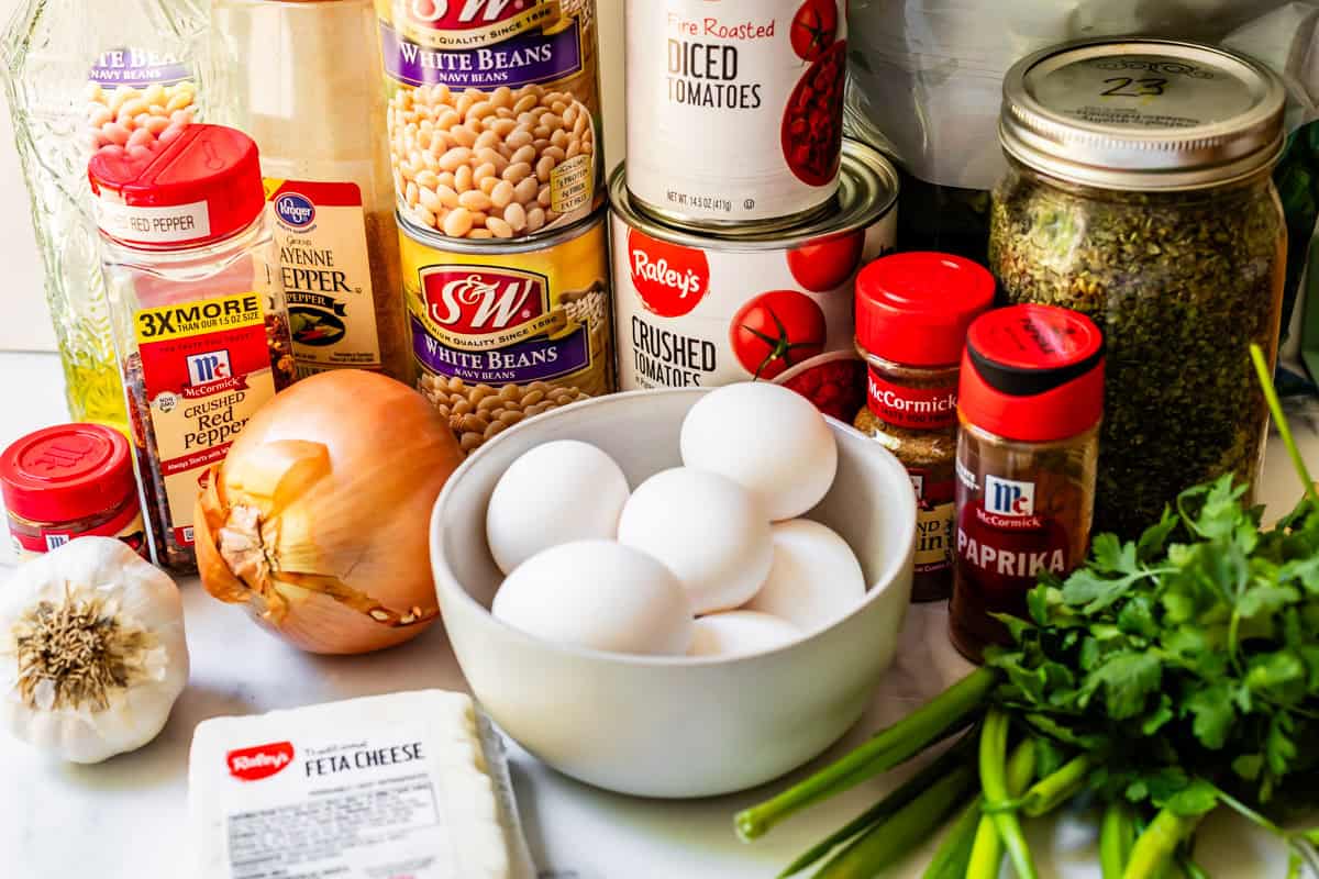 ingredients for shakshuka like canned beans, canned tomatoes, eggs, and more.