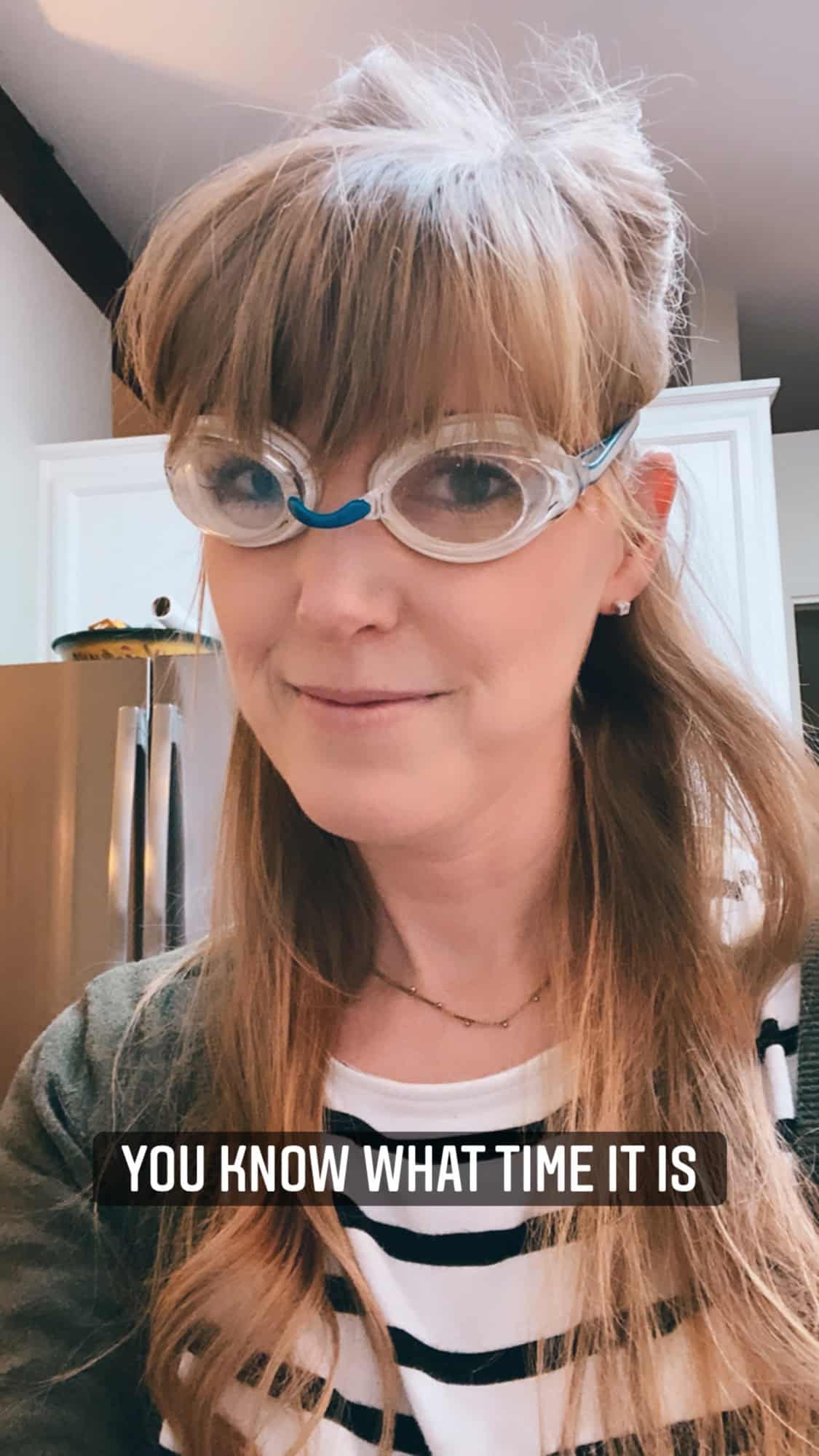 woman wearing swim goggles in a kitchen.