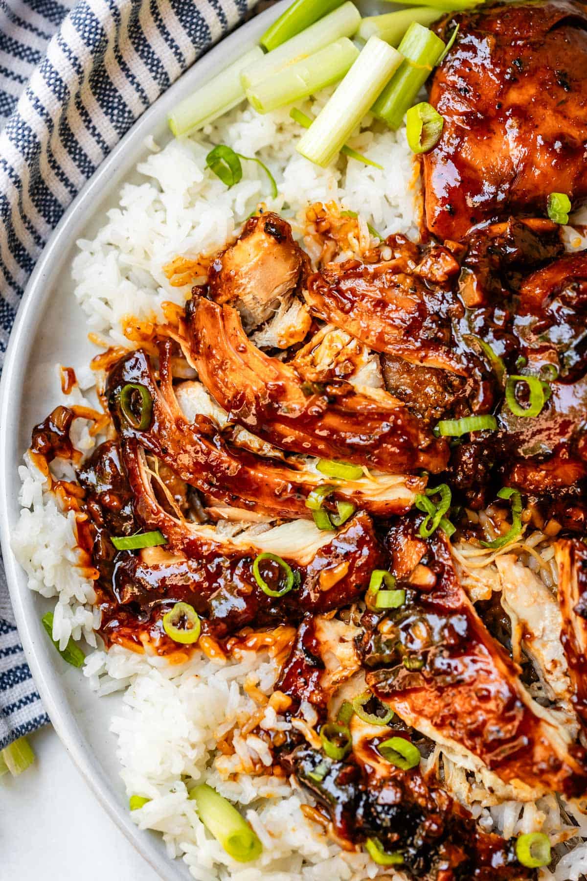 shredded honey garlic chicken over white rice and garnished with green onion.