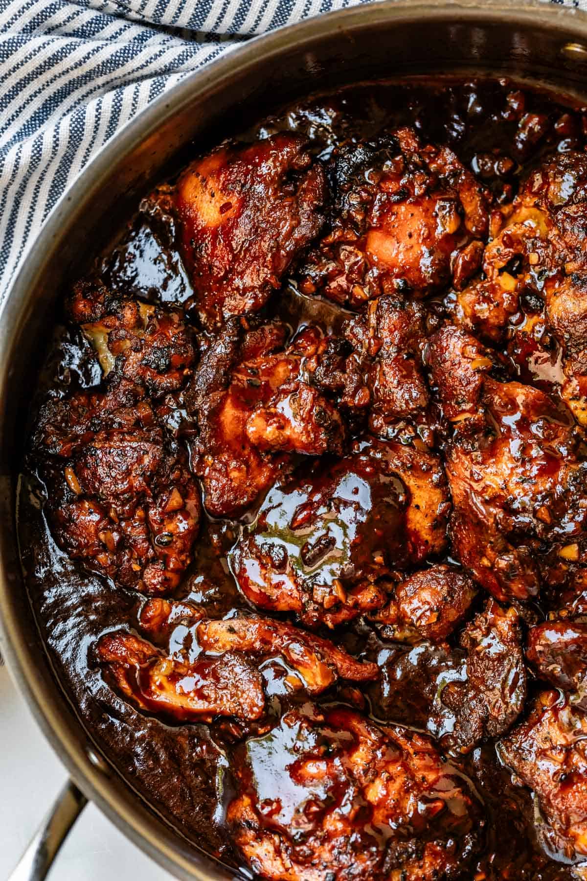 full batch of honey garlic chicken cooked stovetop in a metal skillet.