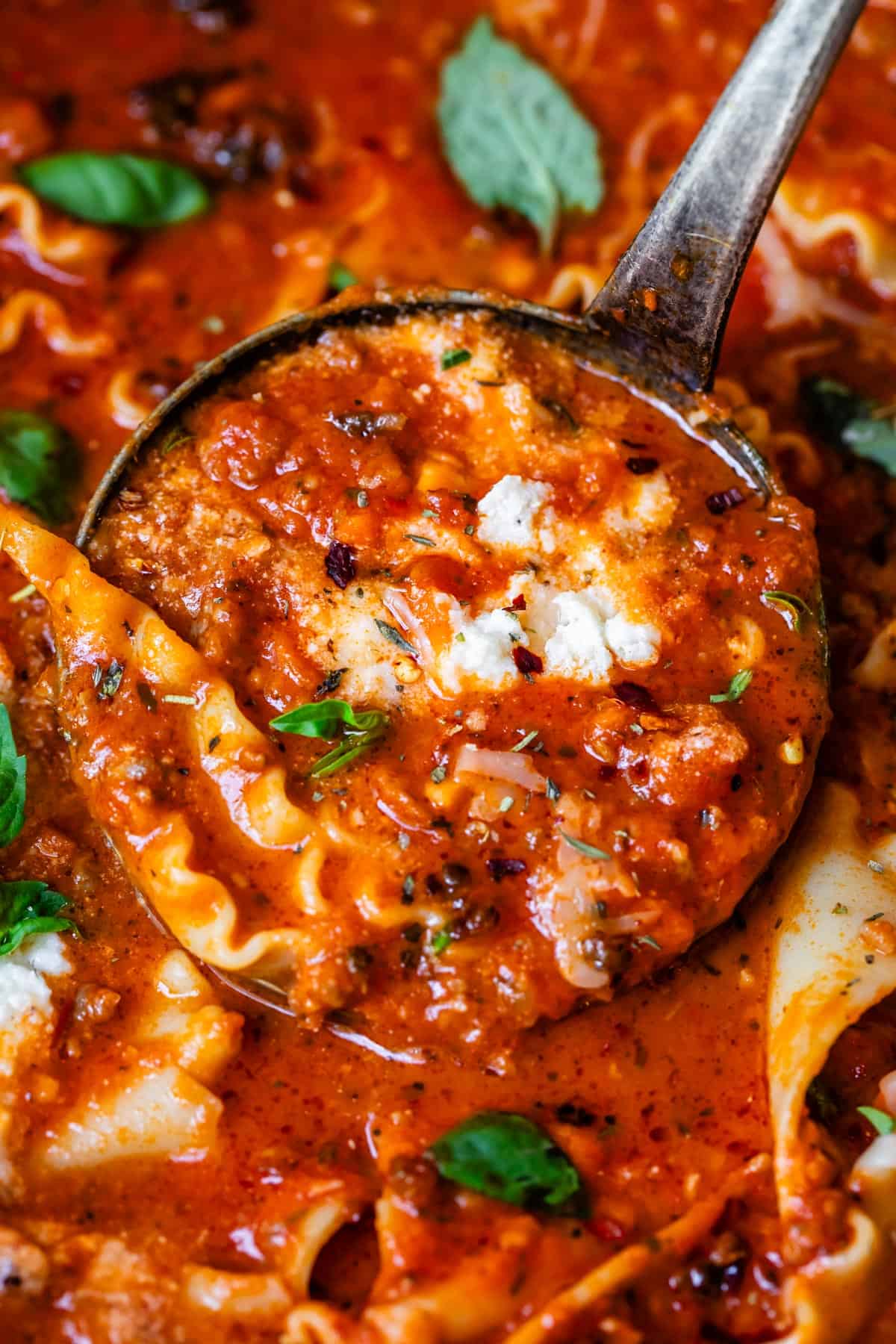 metal ladle with a large scoop of lasagna soup.