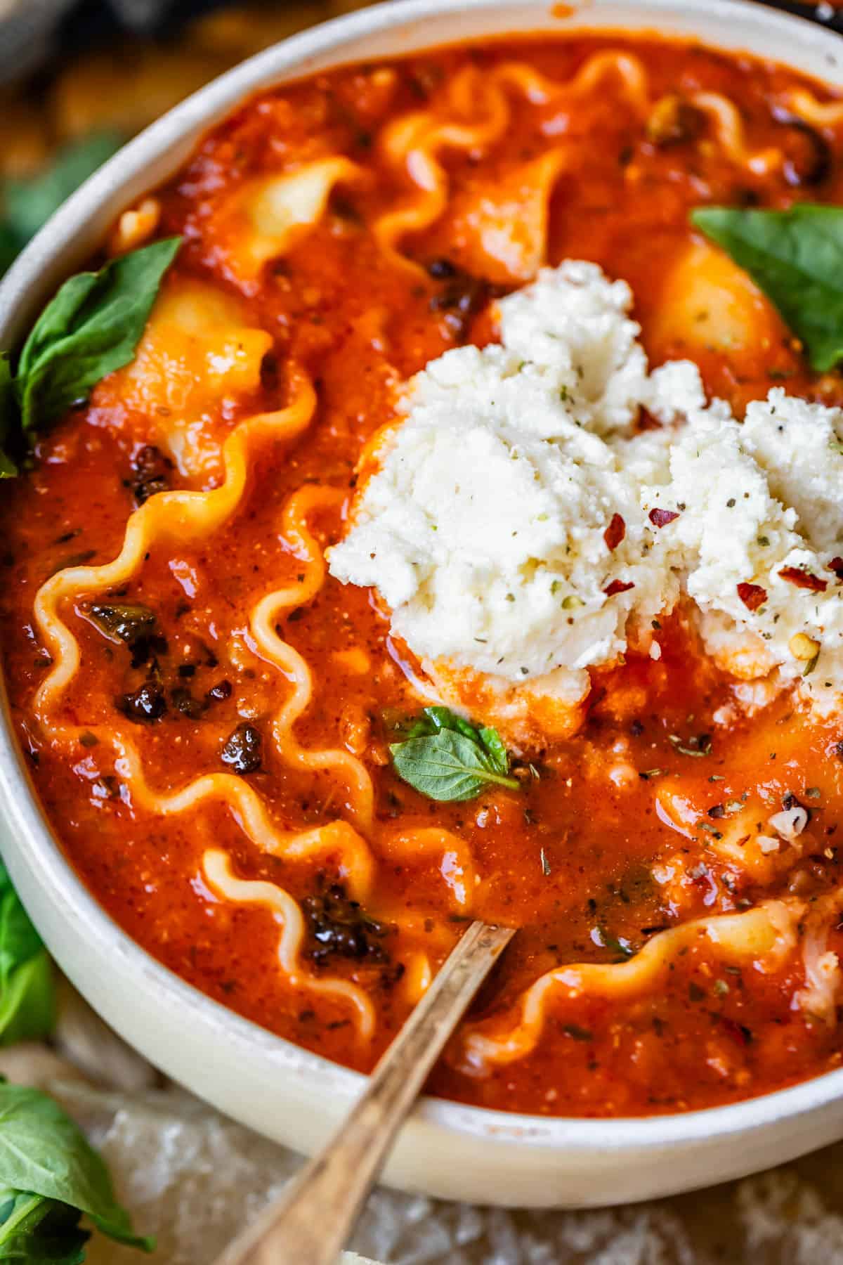 ceramic bowl filled with cozy lasagna soup and creamy ricotta cheese topping.