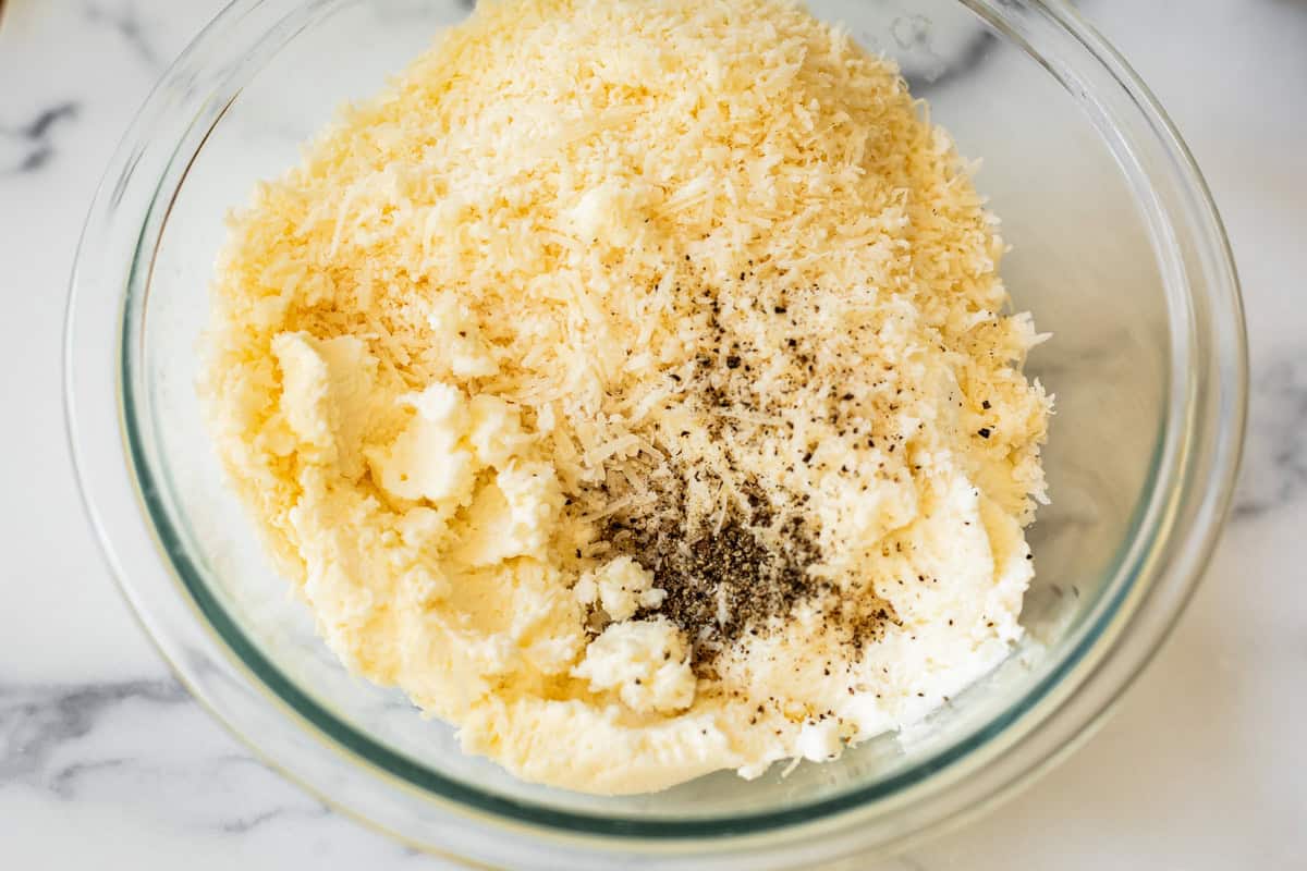 ricotta cheese, parmesan cheese, salt, and pepper in a glass mixing bowl.