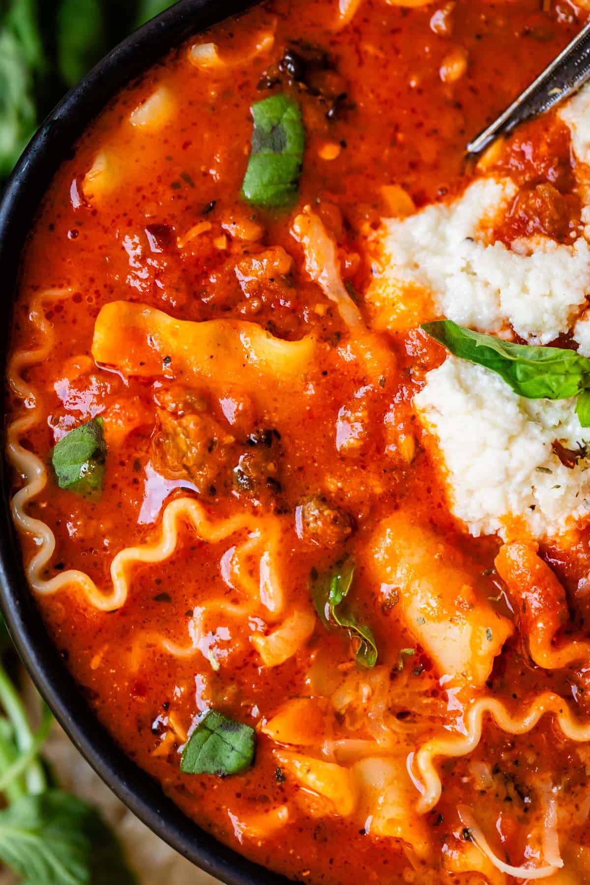 zoomed in view showing the details of lasagna noodles, ricotta topping, and basil garnish.