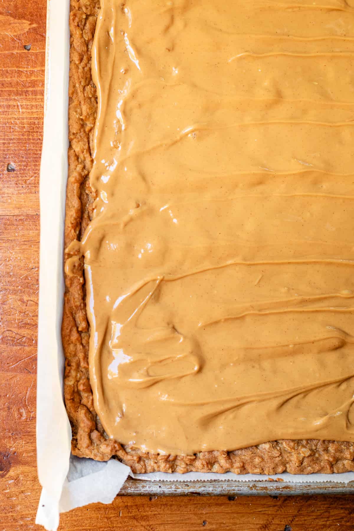 baked oatmeal cookie dough in jelly roll pan with peanut butter layer on top.