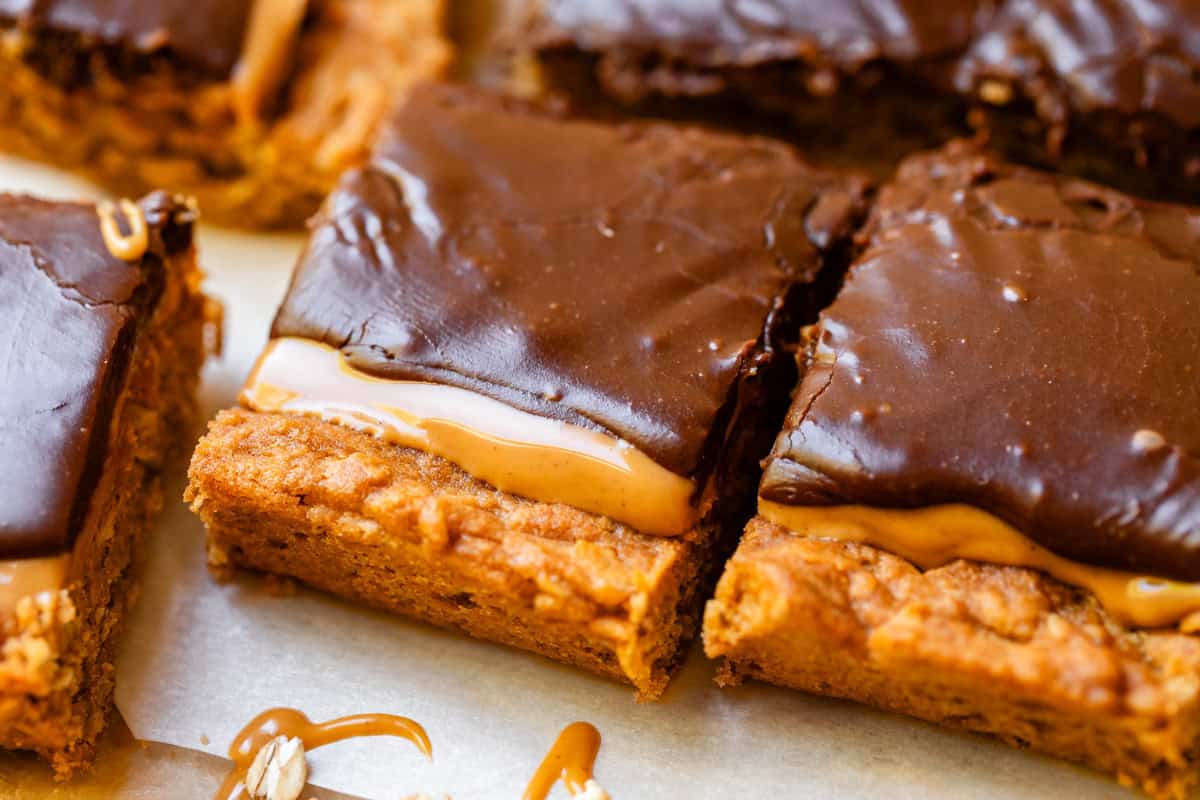 two frosted peanut butter lunch lady bars with oatmeal cookie base on parchment paper.