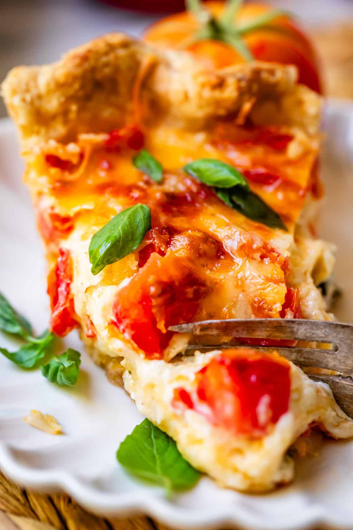 Piece of tomato pie with silver fork getting piece.