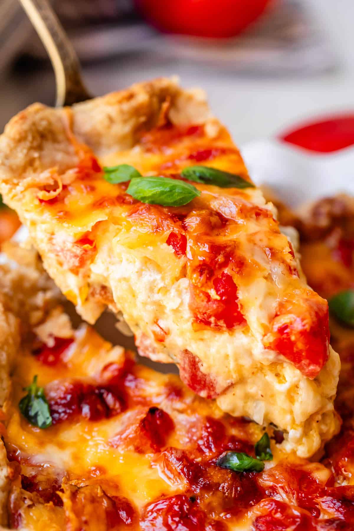 Lifting piece of pie out of tomato pie dish with server.