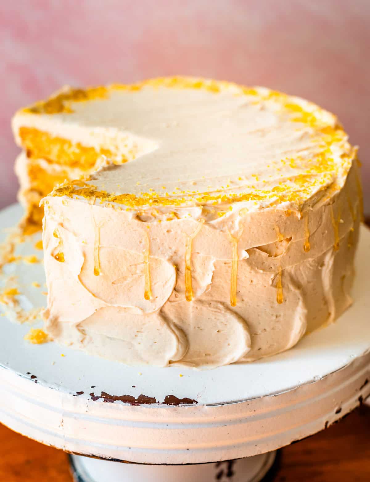 honey cornbread cake with honey drizzle down the sides on a cake pedastal.