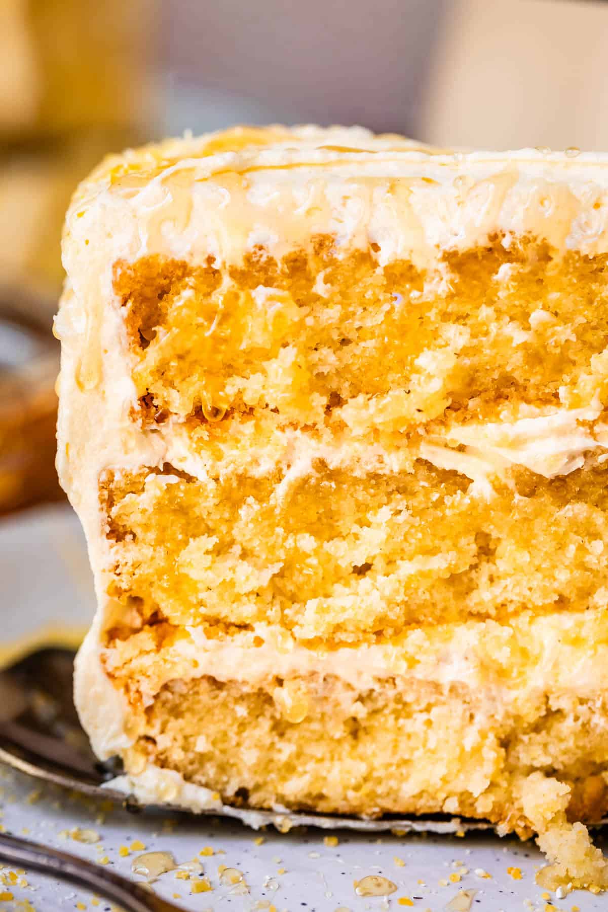 metal serving spatula carrying a piece of three layer cornbread cake with whipped honey frosting.