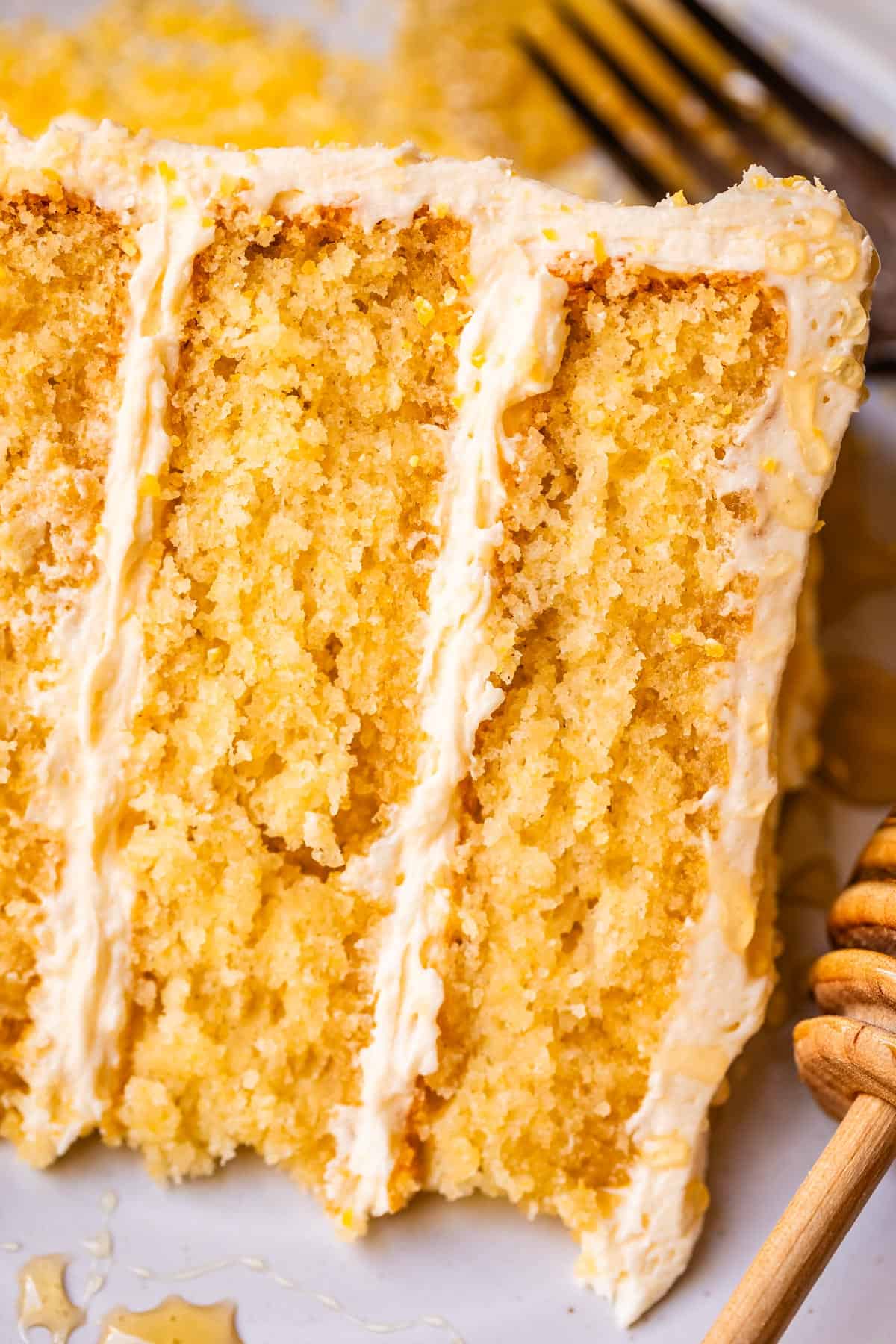 three layered cornbread cake with honey buttercream frosting on a plate.