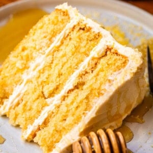slice of honey cornbread cake with whipped buttercream frosting on a plate.