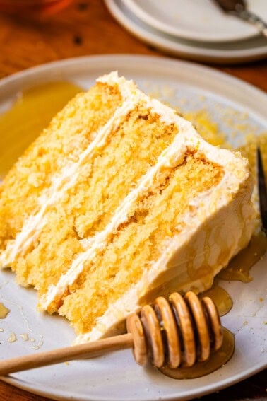 slice of honey cornbread cake with whipped buttercream frosting on a plate.