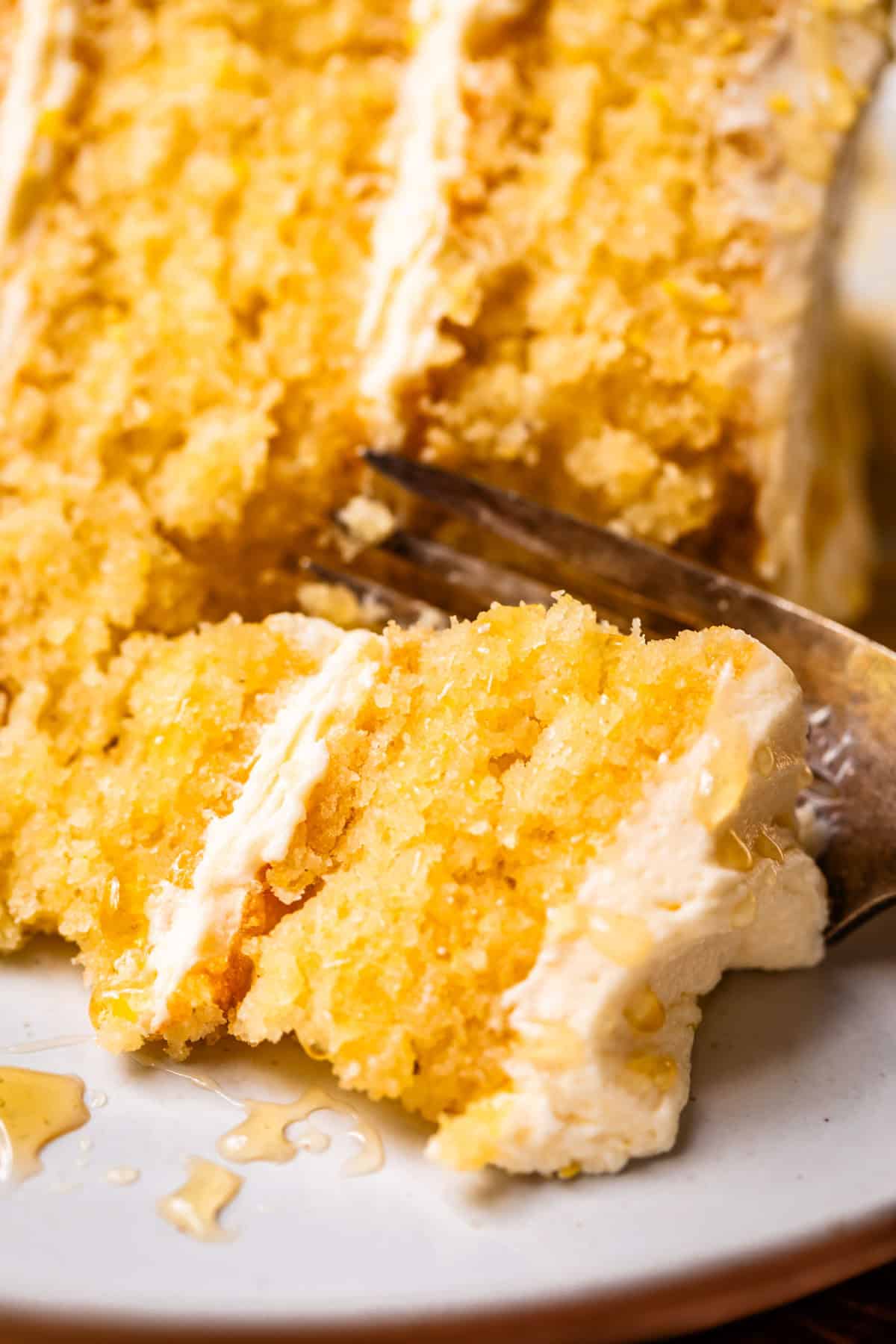 fork picking up a bite of cornbread cake from a slice on a plate.