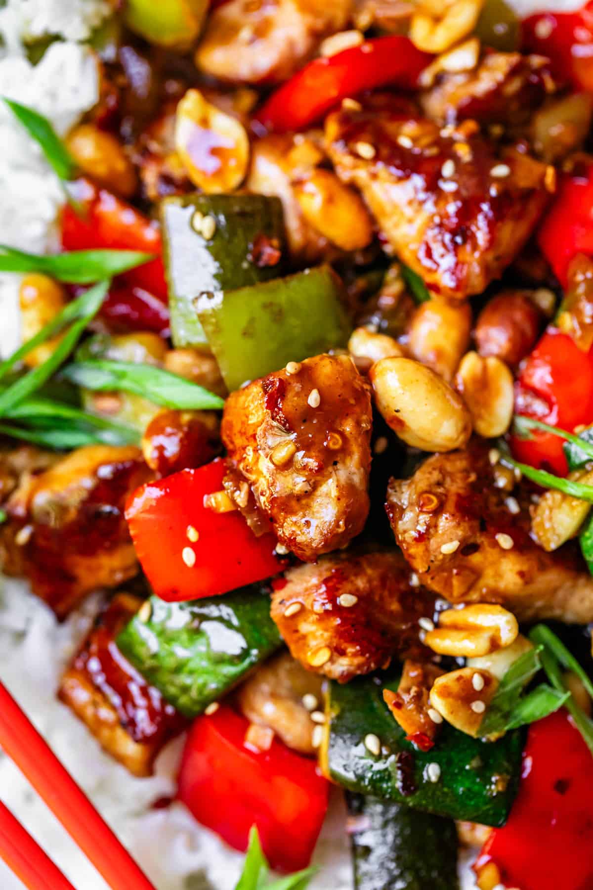 Kung Pao chicken close up with peanuts and veggies and part of some chop sticks.