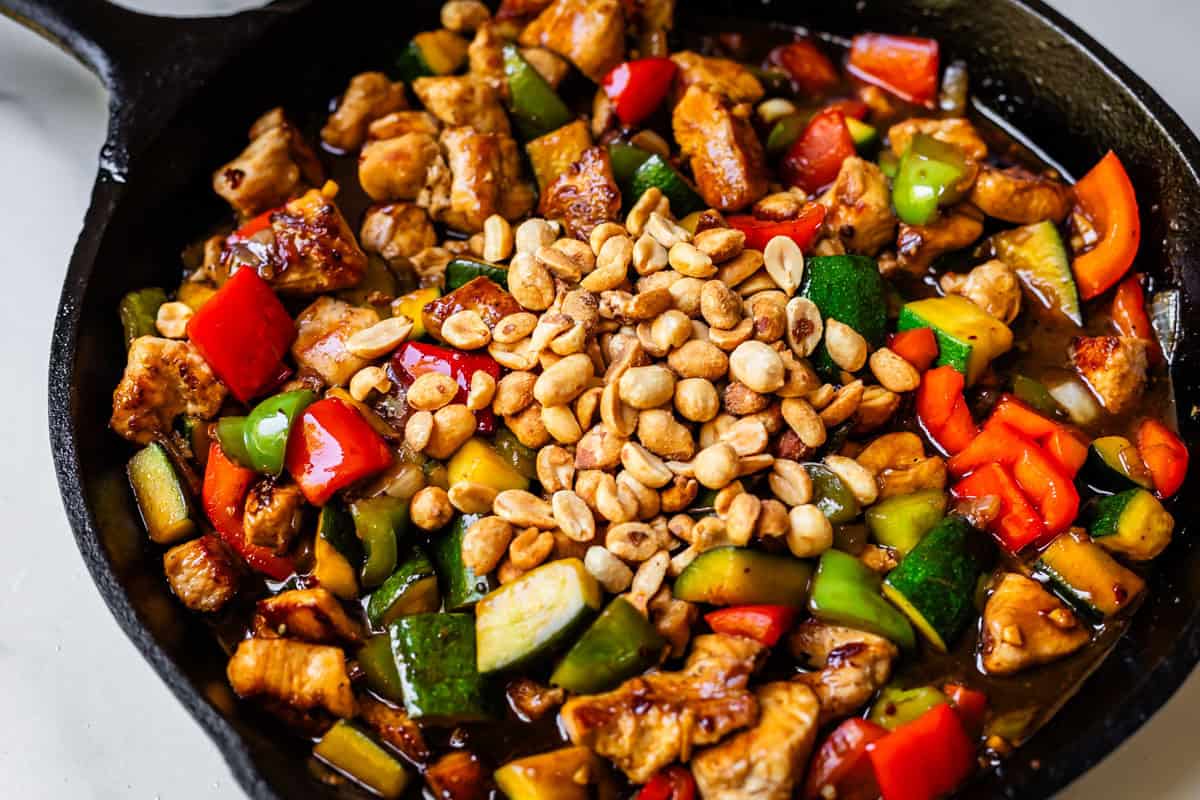 cooked kung pao chicken in cast iron skillet and topped with peanuts.