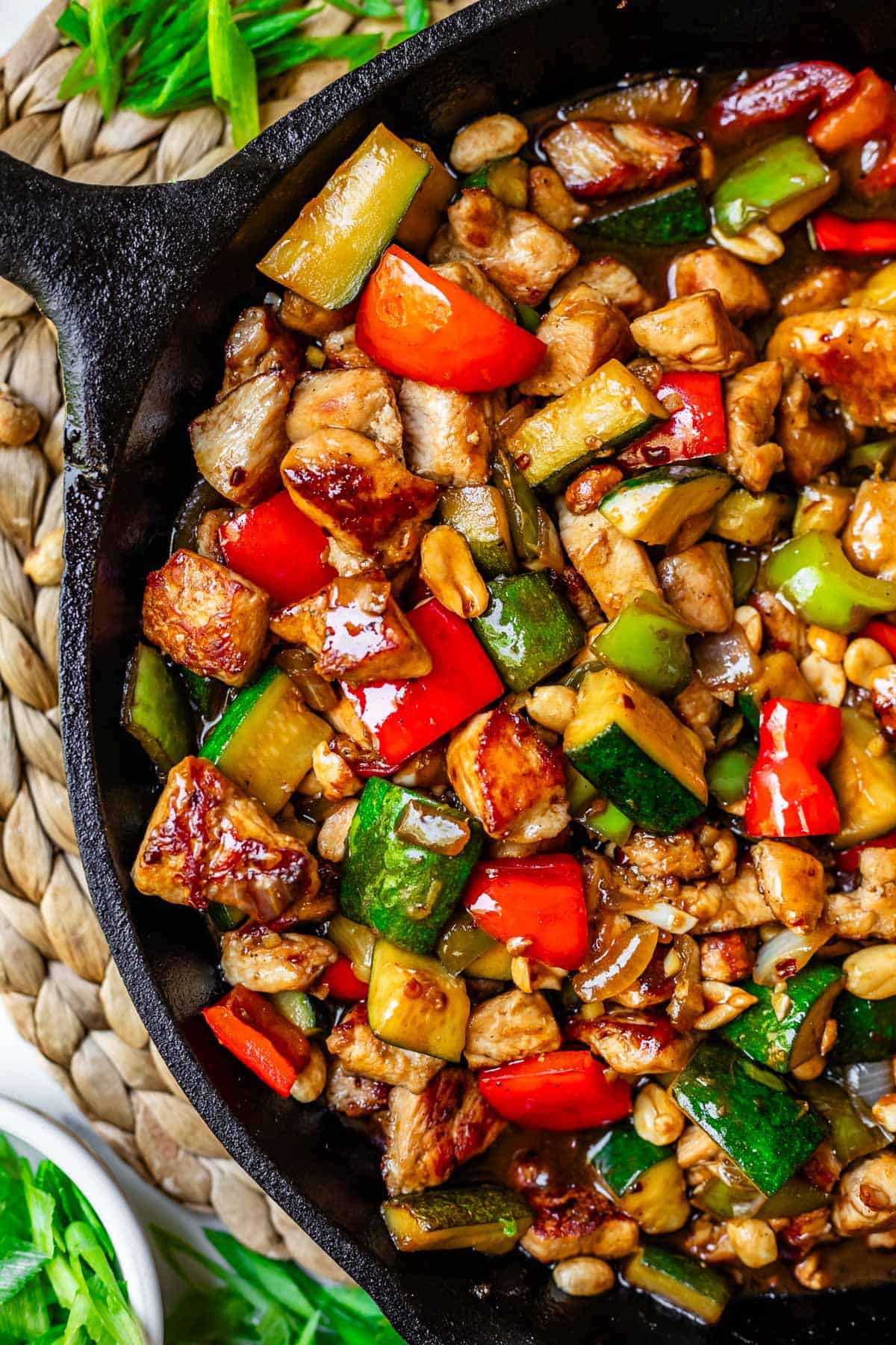Overhead shot of chicken, zucchini, peppers, and peanuts in an Asian sauce.