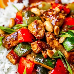 Kung pao chicken with zucchini and bell peppers and green onions on rice.