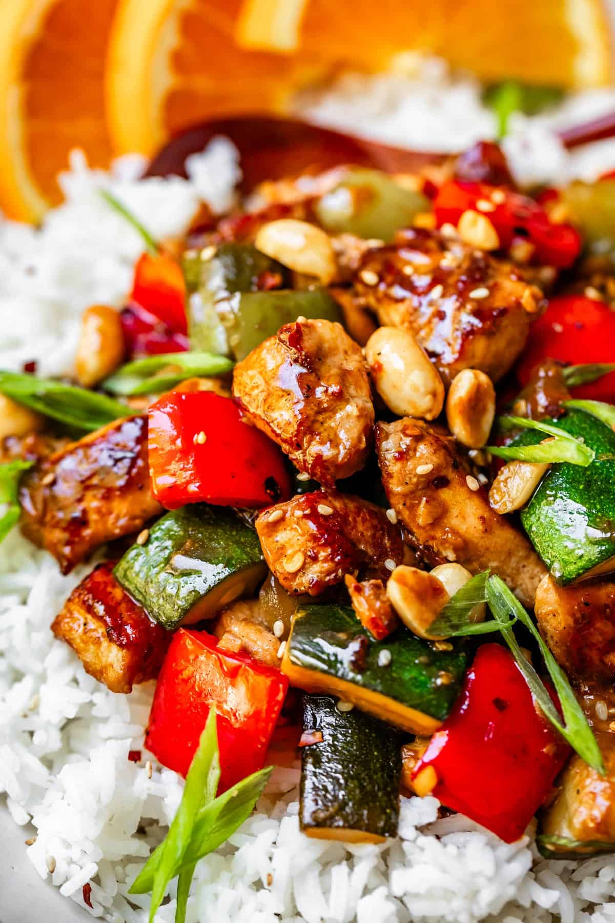 Kung pao chicken with zucchini and bell peppers and green onions on rice.