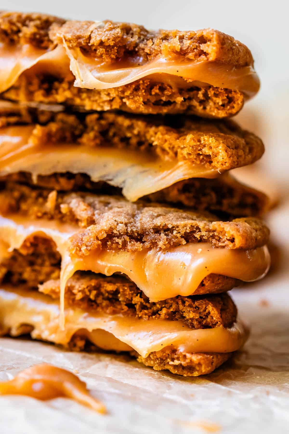 a stack of 4 cookie sandwiches torn in half showing the gooey caramel center.