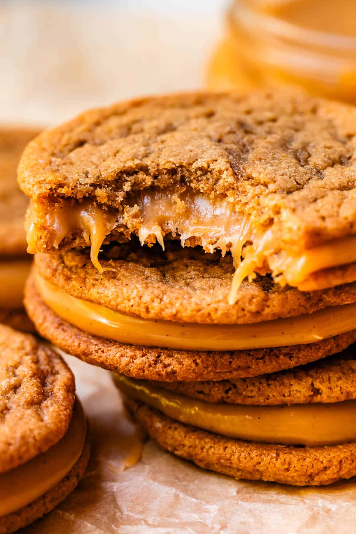 cookie with a bite take from it stacked on top of two other caramel sandwich cookies.