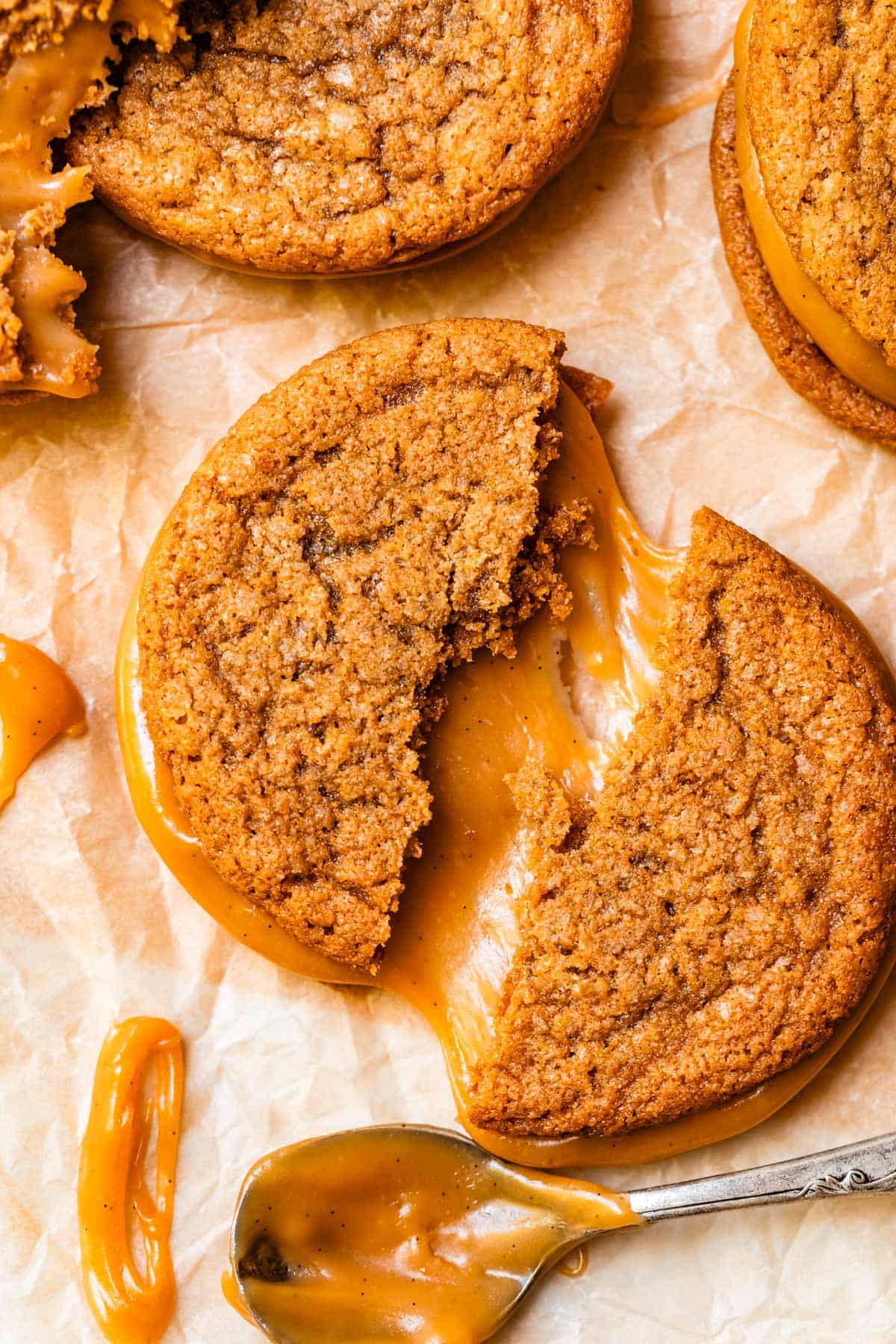 a salted caramel sandwich cookie torn into two pieces showing the fudgy caramel center.