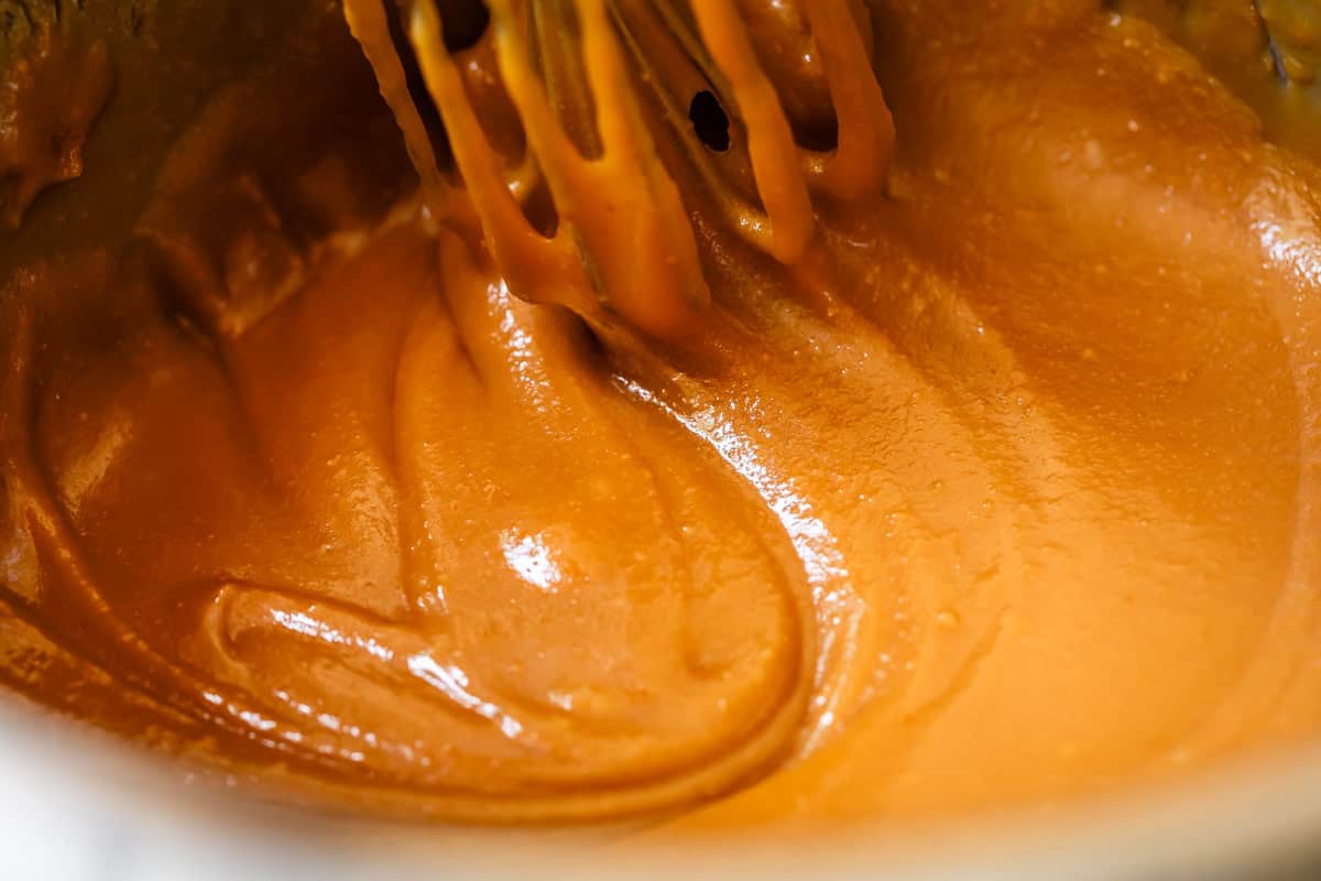 close up of caramel in a pot with a wisk.