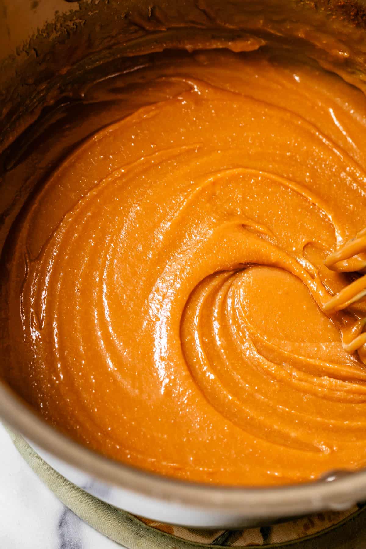 whisking caramel sauce in a pot.