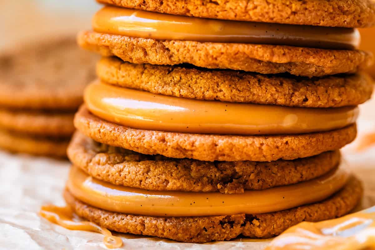 stack of three salted caramel cookie sandwiches showing specks of vanilla in the caramel.
