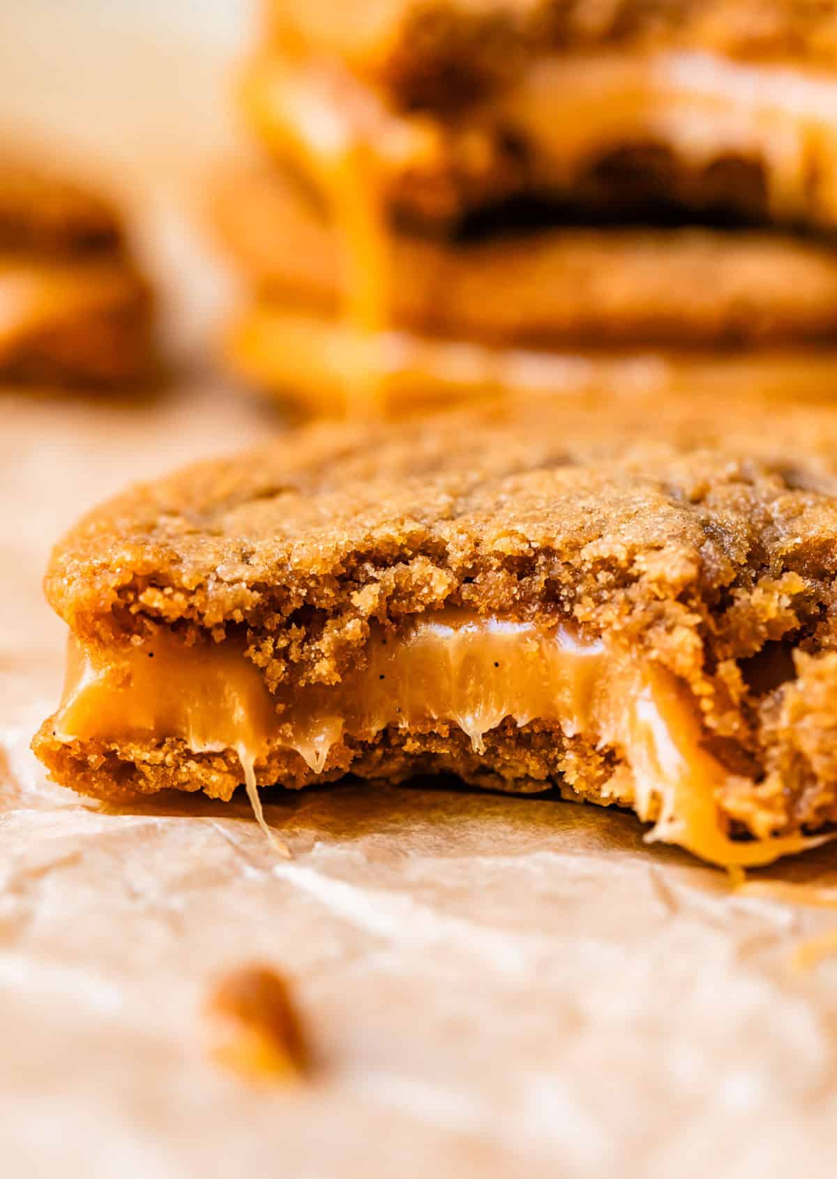 a salted caramel cookie sandwich with a bite taken from it, showing a thick layer of caramel.