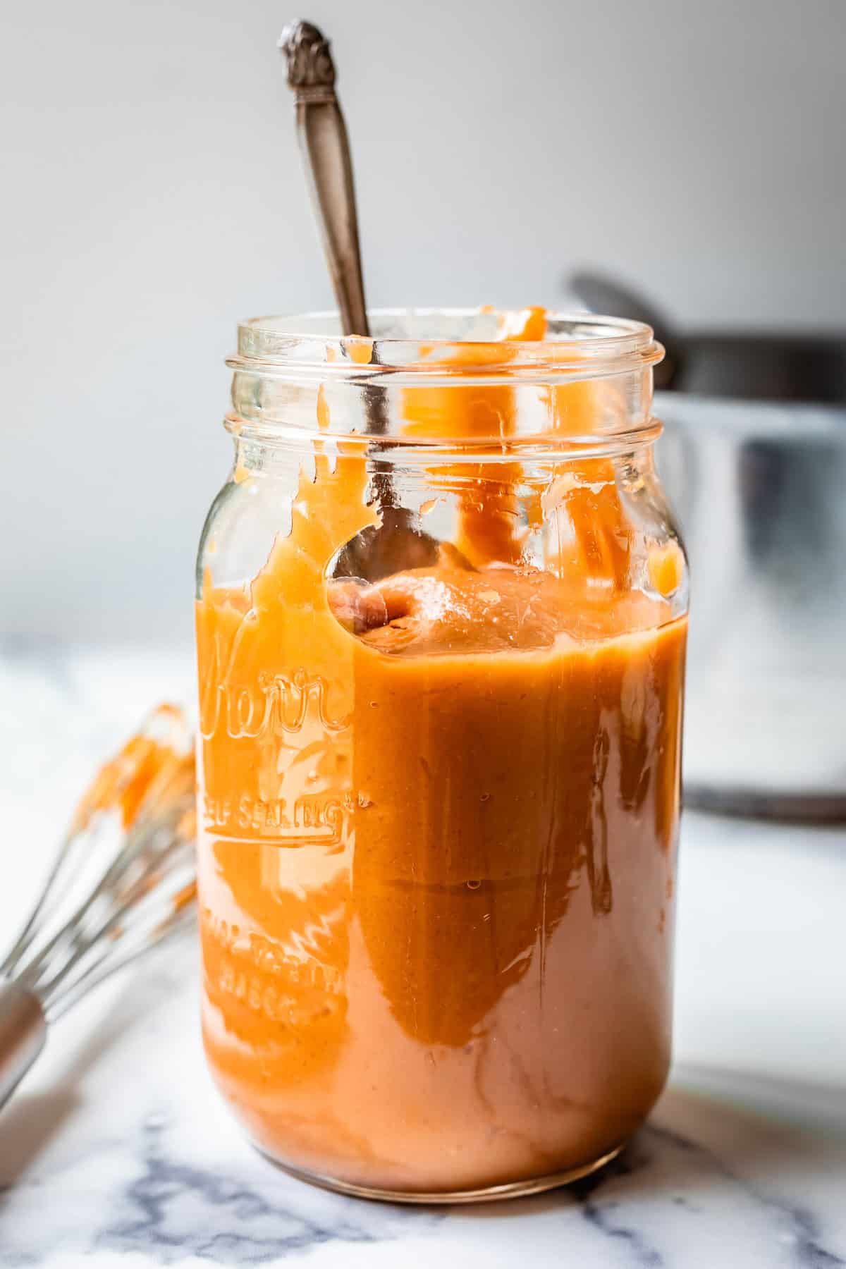 metal spoon stuck into a quart size mason jar of salted caramel.