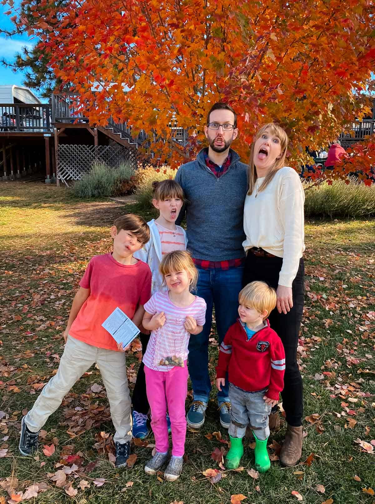 family making silly faces in front of fall leaves.