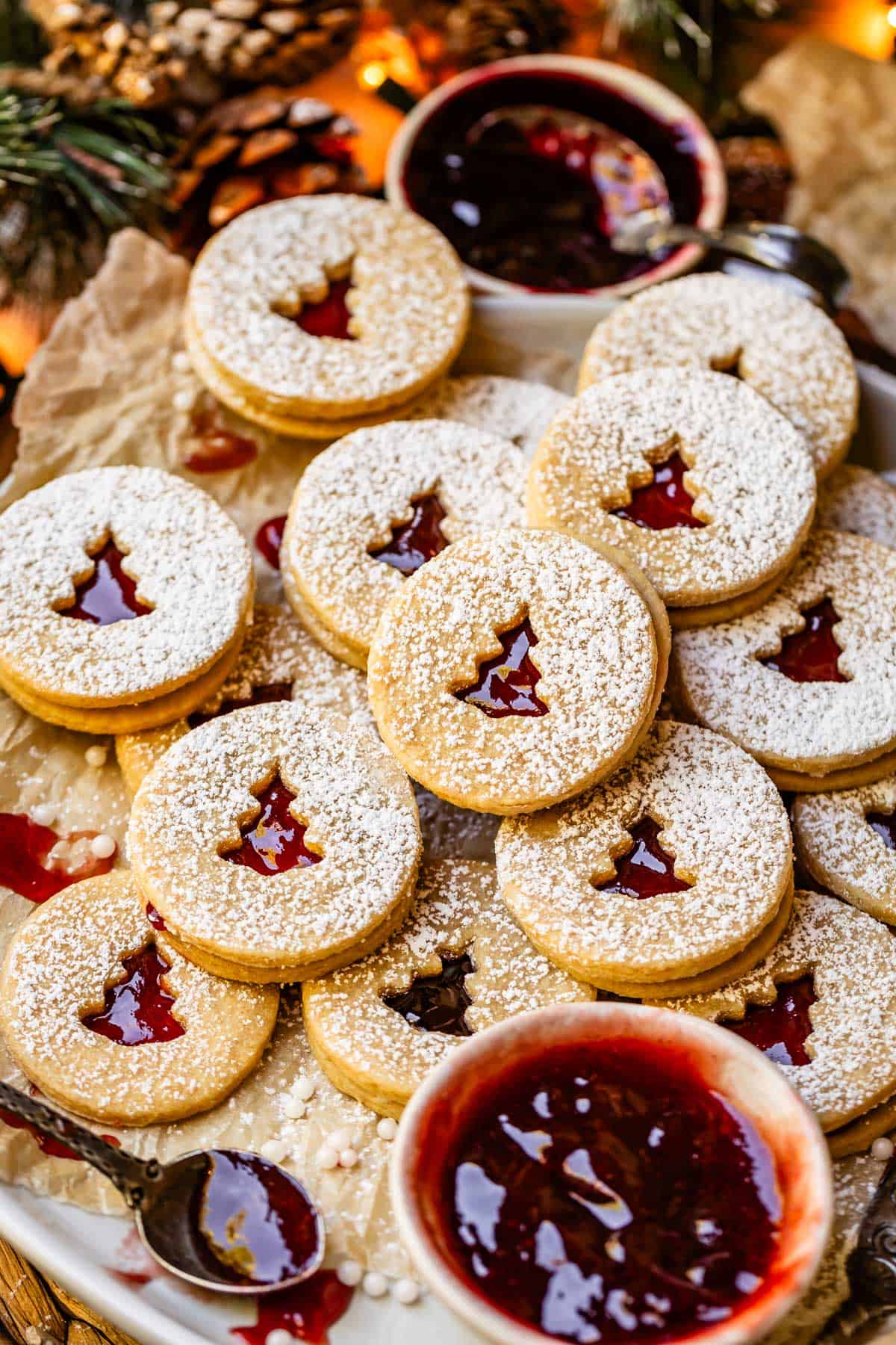 a platter stacked with linzer cookies and a bowl of raspberry jam.