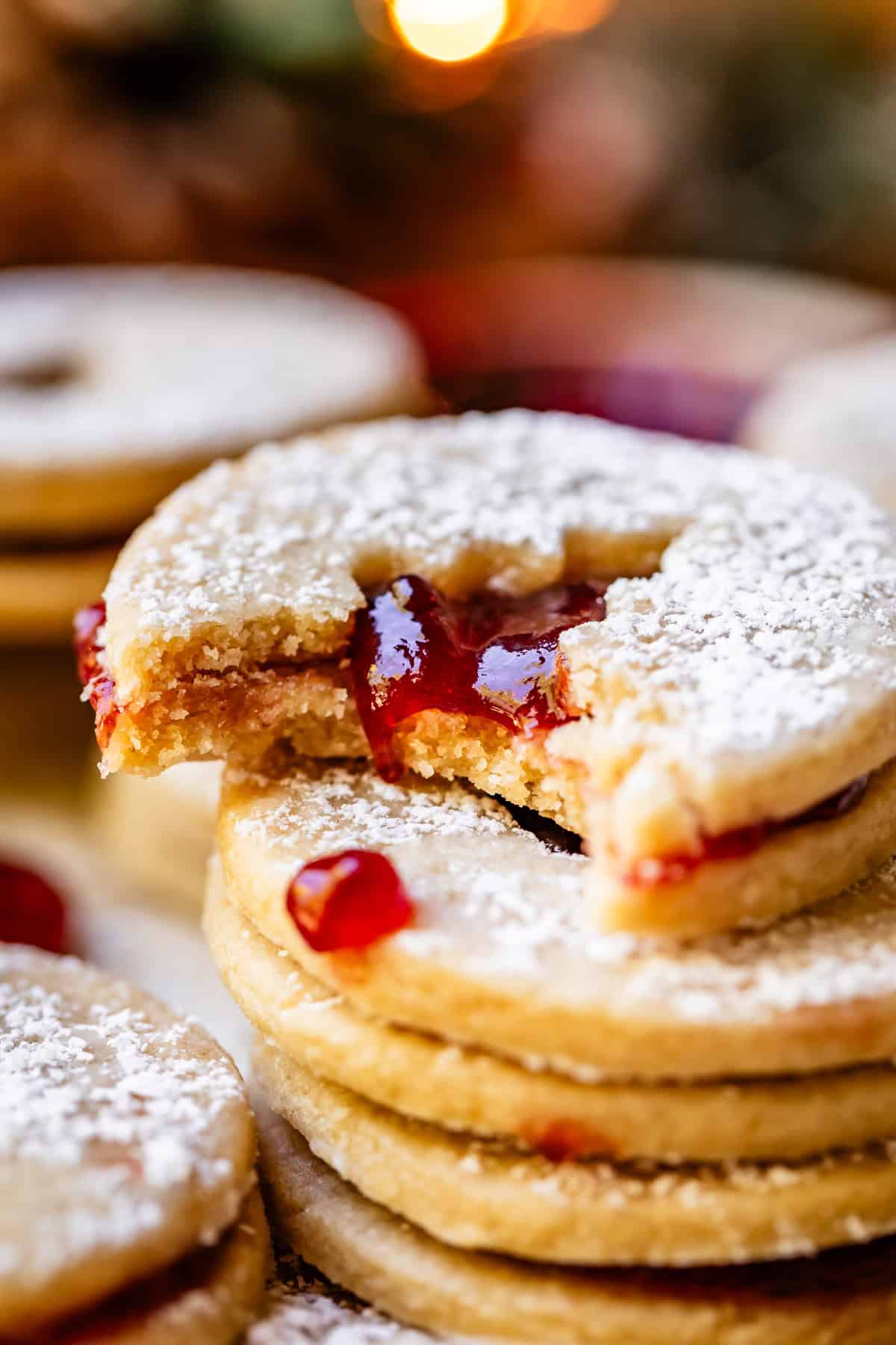 linzer cookie with a tree cutout and jam, with a bite taken from it.